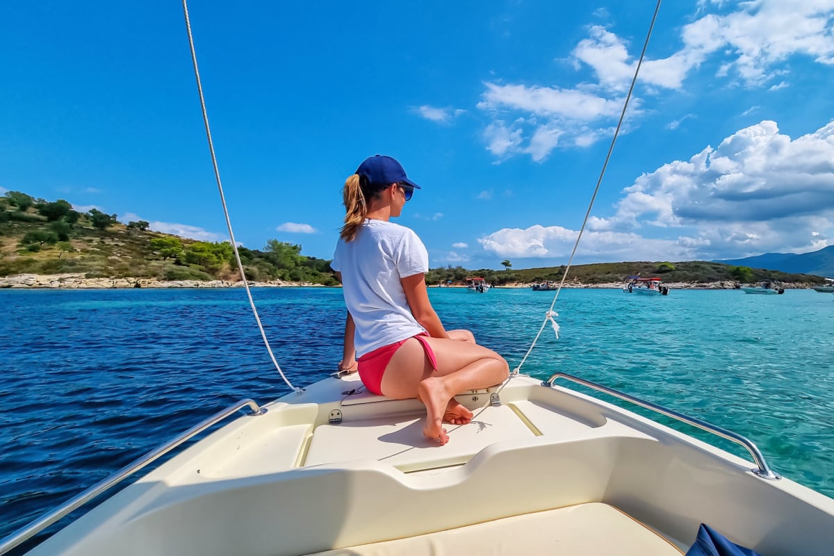 Woman on a boat in the blue lagoon of Vourvourou on peninsula Sithonia, Chalkidiki (Halkidiki), Greece